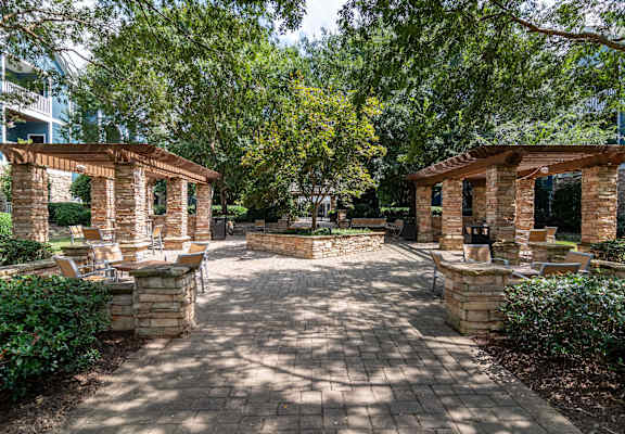 a patio with brick pillars and trees and benches