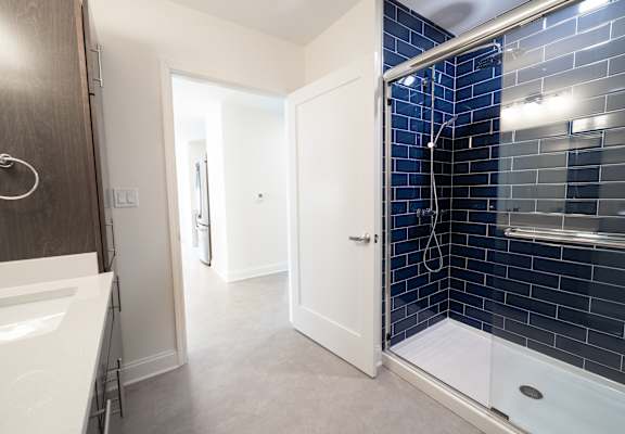 A bathroom with a white sink and a blue tiled shower at The Annex Apartment, Buffalo, NY, 14222