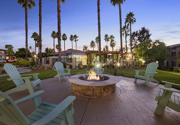 a fire pit with chairs around it at dusk