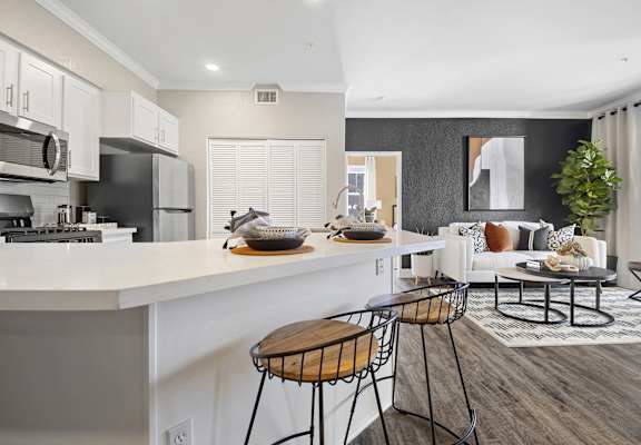 an open kitchen and living room with a white counter and stools