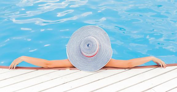A woman in a striped hat is relaxing by the pool.