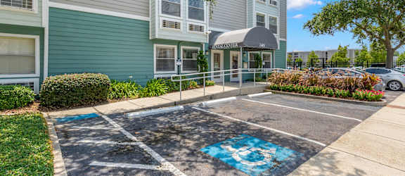 A parking lot in front of a building with a blue painted symbol on the pavement.
