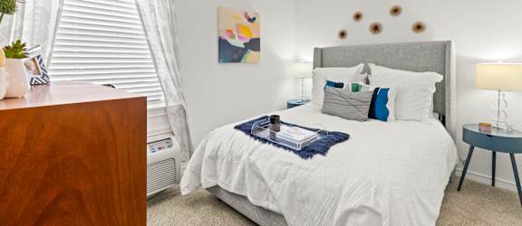 A bedroom with a white bed and a wooden dresser.