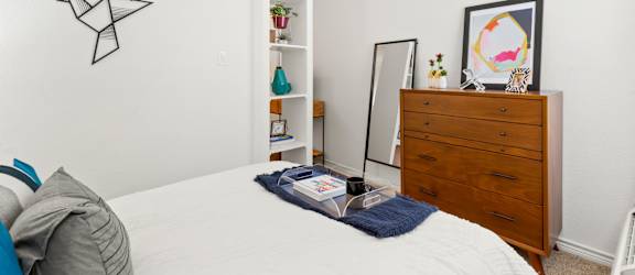 A bedroom with a bed, a dresser, and a mirror.