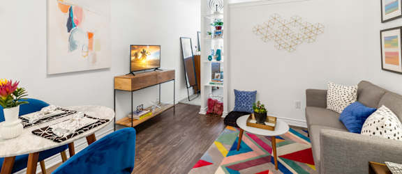 A living room with a white ceiling fan and a painting on the wall.