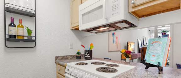 A kitchen with a white stove top oven and a white microwave above it.