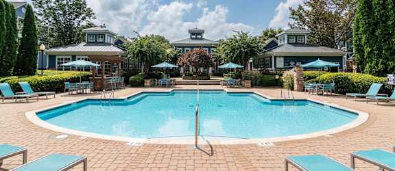 a swimming pool with chairs and umbrellas at the resort on a sunny day