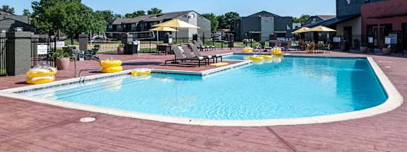 a swimming pool with tables and umbrellas at a resort