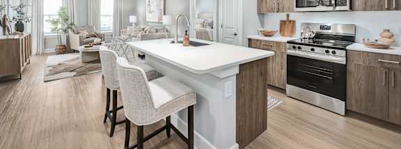 A modern kitchen with a white island and wooden cabinets at The Ashton at East Park Apartments, Kennesaw, GA, 30144