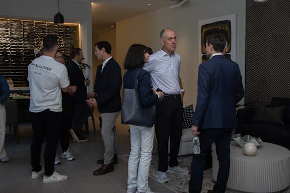A group of people are standing in a room talking to each other.