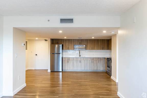 A kitchen with a refrigerator, sink, and stove.
