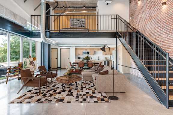 A living room with a black and white checkered rug and a staircase.
