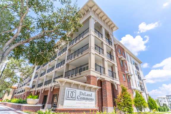 A building with a sign that says "Deland Commons" in front of it.