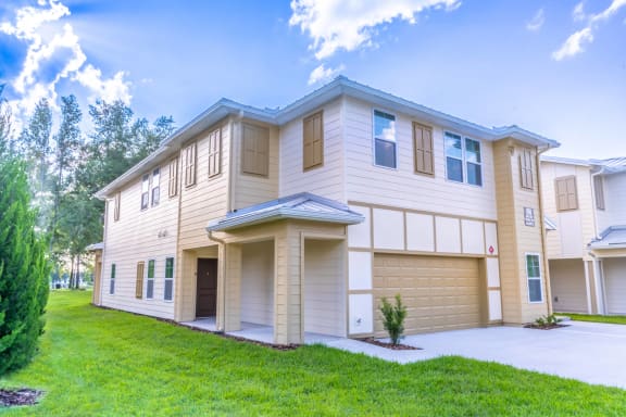 a beige and white house with a driveway and grass