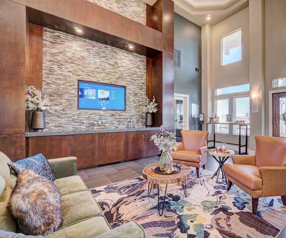 The front office and resident lounge with couches, a TV embedded in a stone wall, and a coffee table at Villas at Countryside Apartment Homes. 