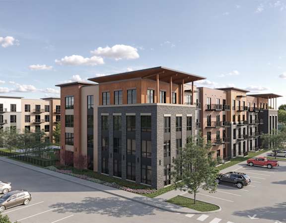 A modern apartment complex with a parking lot in front.
