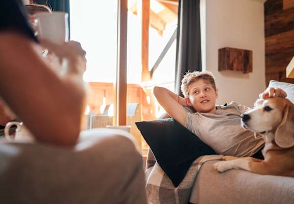 Kid and dog lounging on the couch with parent
