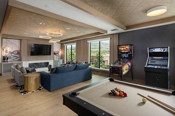 A billiard table is in the middle of a living room with a television and a fireplace.
