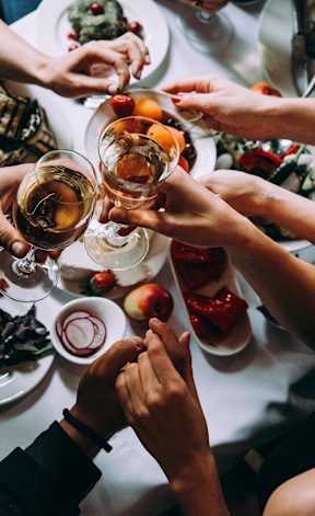 A group of people toasting with drinks at a dinner table.