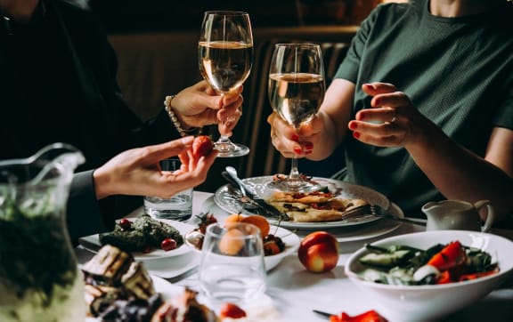 people sitting at a table with food and wine glasses