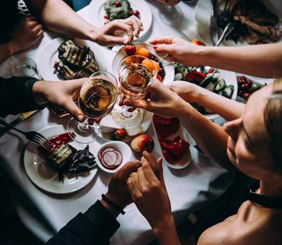 A group of people toasting with drinks at a dinner table.