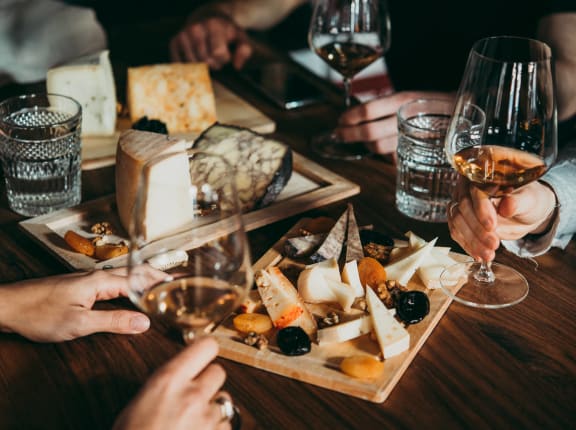 people sitting around a table with plates of cheese and wine