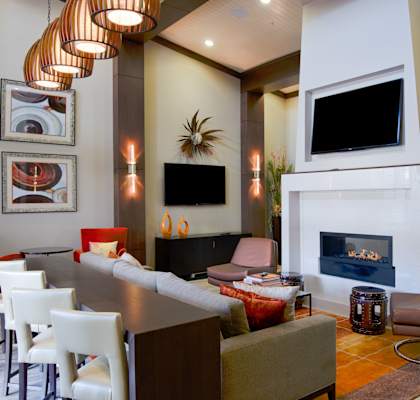 Elegant clubhouse lounge at Residences at Prairiefire with modern fireplace, flat-screen TVs, and contemporary seating. at Residences at Prairiefire Apartment Homes, Kansas