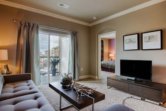 Stylish living room with balcony access and modern décor  at Residences at Prairiefire Apartment Homes, Overland Park, KS, 66223