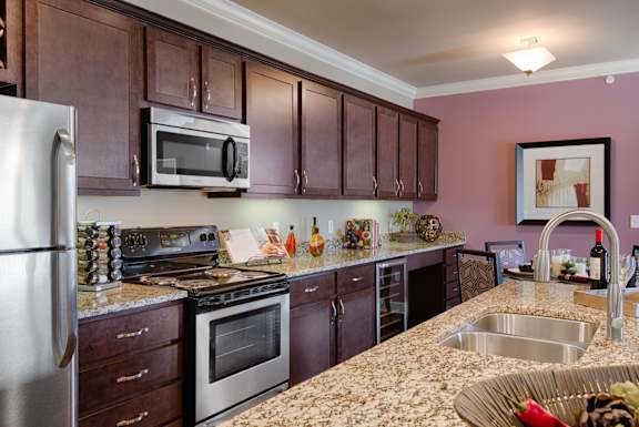 Elegant kitchen with granite countertops, stainless steel appliances, and wine storage  at Residences at Prairiefire Apartment Homes, Overland Park