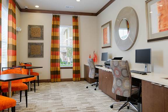 Business center at Residences at Prairiefire with computer stations, modern décor, and vibrant orange seating. at Residences at Prairiefire Apartment Homes, Overland Park