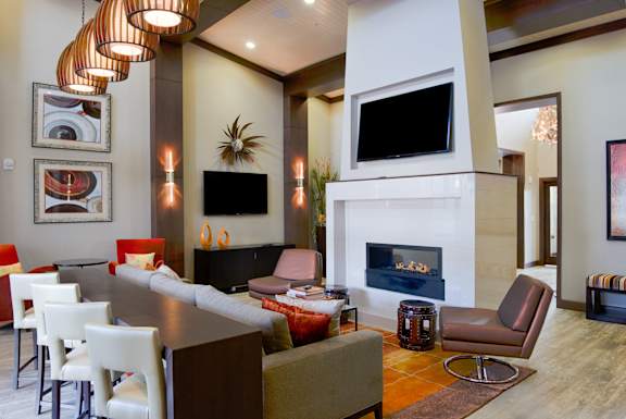 Elegant clubhouse lounge at Residences at Prairiefire with modern fireplace, flat-screen TVs, and contemporary seating. at Residences at Prairiefire Apartment Homes, Overland Park, Kansas