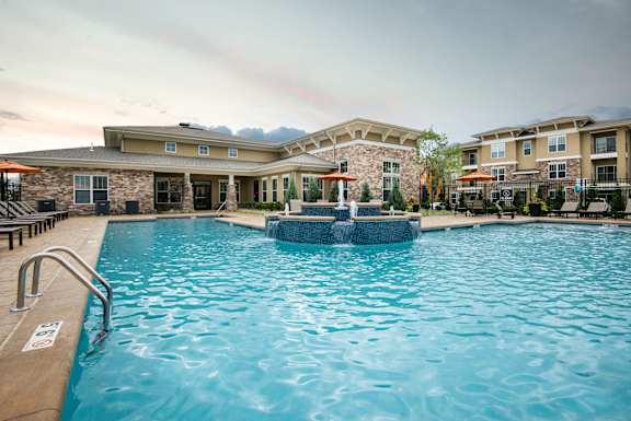 Sparkling pool with central fountain and clubhouse backdrop  at Residences at Prairiefire Apartment Homes, Kansas