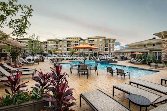 Resort-style pool area at Residences at Prairiefire in Overland Park, KS with lounge chairs, umbrellas, and landscaped surroundings. at Residences at Prairiefire Apartment Homes, Overland Park, KS, 66
