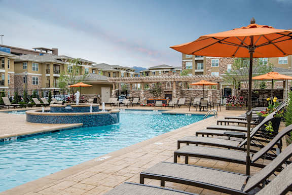 Large swimming pool with orange umbrellas and sun loungers  at Residences at Prairiefire Apartment Homes, Overland Park, KS