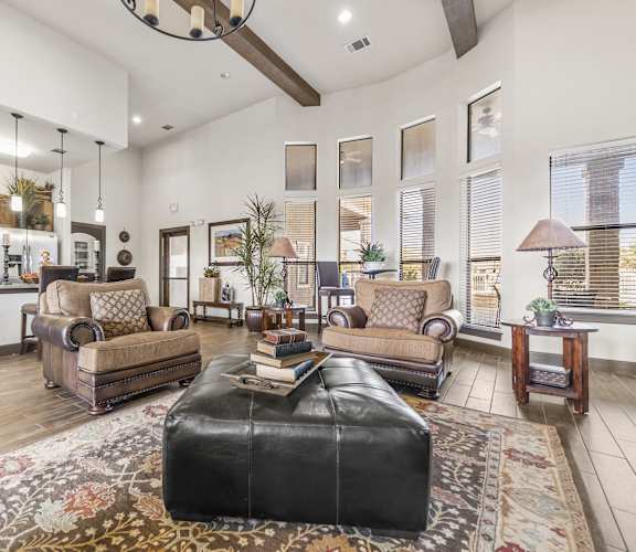 a living room with a leather ottoman and a leather couch