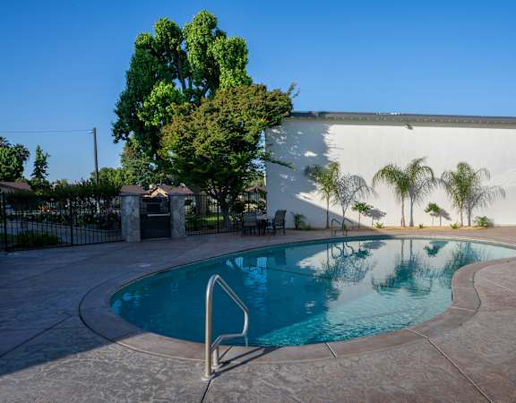 A pool with a diving board in front of a white building.