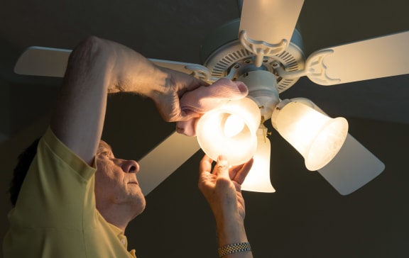 Man cleaning ceiling fan at Mirabella Apartments, Bermuda Dunes, California