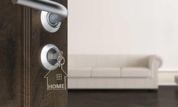 a door with a key in the door handle with a house keychain on it