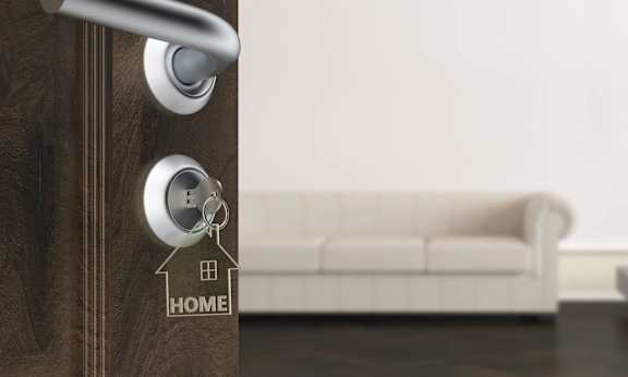 a door with a key in the door handle with a house keychain on it