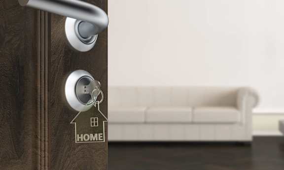 a door with a key in the door handle with a house keychain on it