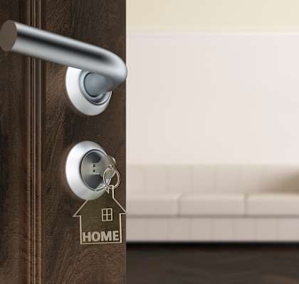 A modern door handle with a keyhole and a key on a wooden door.