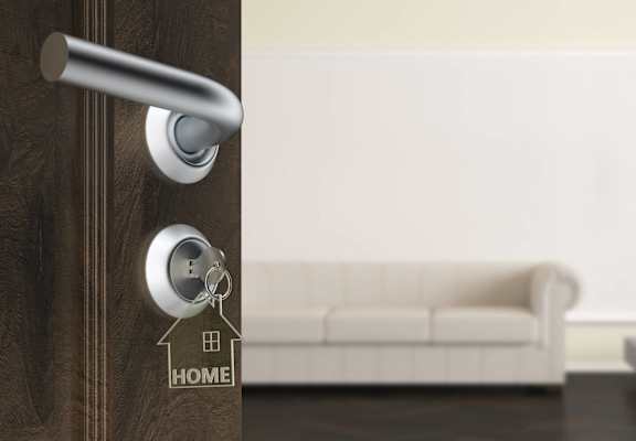 a door with a key in the door handle with a house keychain on it