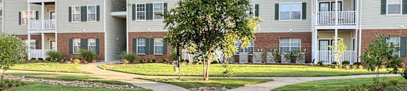 an exterior view of an apartment building with a sidewalk at The Madison Apartment Homes in Tyler, 75703