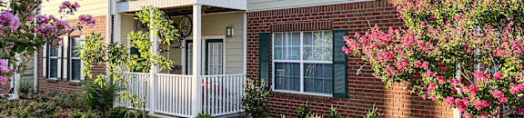 a sidewalk in front of a brick house with a balcony at The Madison Apartment Homes in Tyler, TX