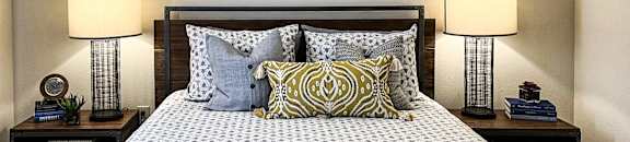a bedroom with a bed and two night stands with lamps at The Madison Apartment Homes in Tyler, Texas