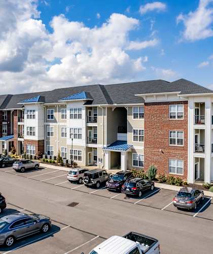 an apartment complex with cars parked in a parking lot