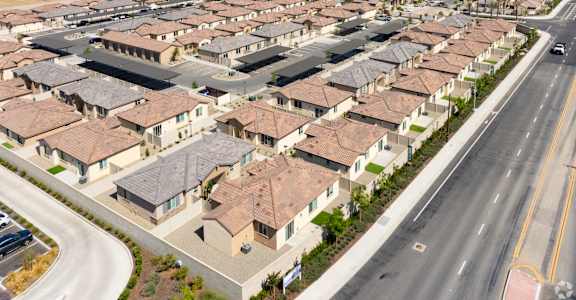 A large suburban housing development with rows of houses and a road running through it.