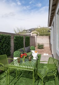 a patio with green chairs and a table with flowers on it