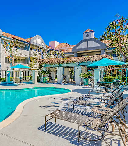 a swimming pool with lounge chairs and umbrellas