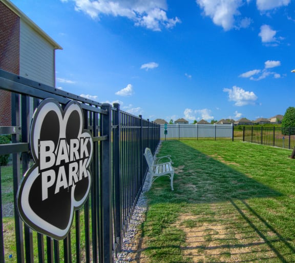a fenced in yard with a bench and a sign that reads bark park
